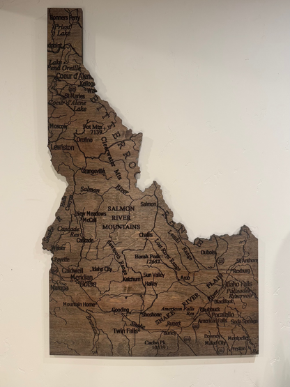Wooden map of Idaho with engraved text on a white wall
